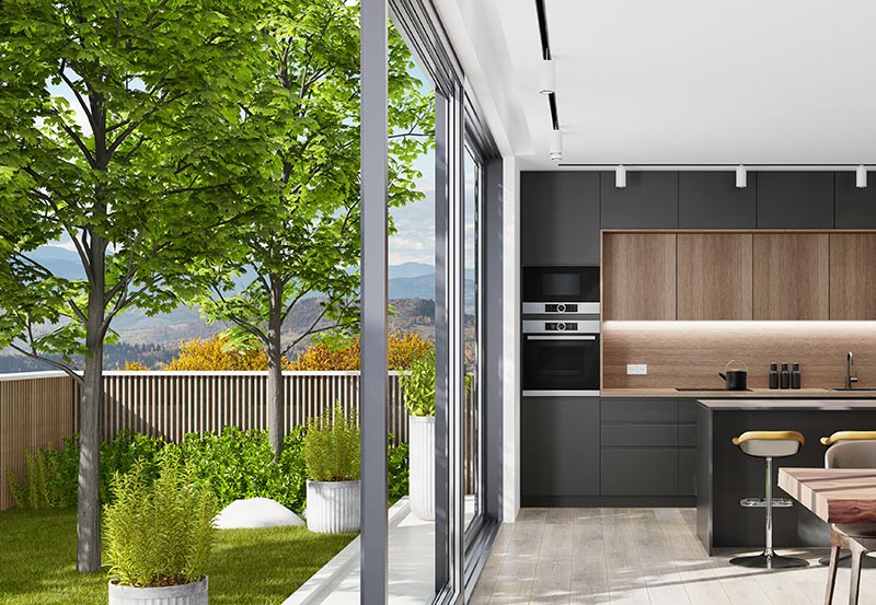 Country villa interior with small garden. Modern black Italian style open concept kitchen with island table with three stools and lots of natural light.